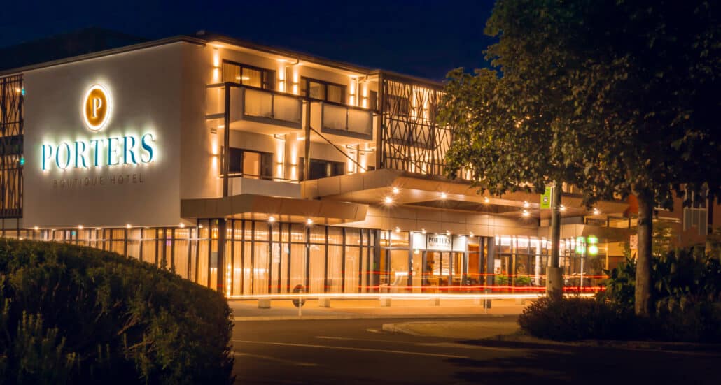 Boutique Accommodation Napier: Porters Boutique Hotel facade is lit up and glowing in the Hawke's Bay twilight.